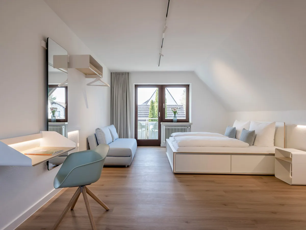 Dachgeschoss-Apartment mit Schreibablage, Garderobe und Bett mit Schubladensockel