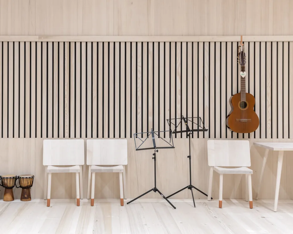 Musikraum mit Akustik-Lattenwand, aufgehängter Gitarre und Notenständern